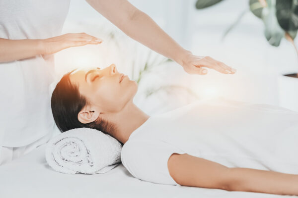 Woman lying with eyes closed receiving calming energy therapy treatment