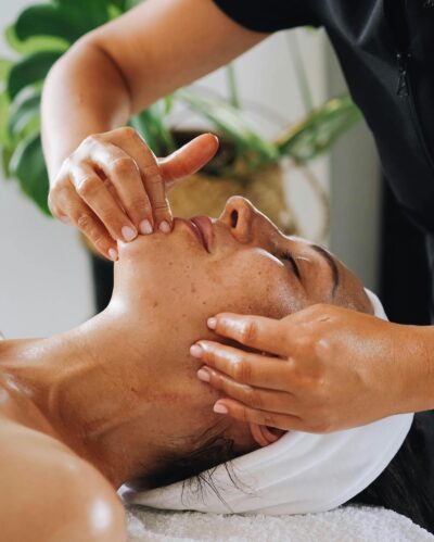 Woman being treated with facial massage by spa masseuse