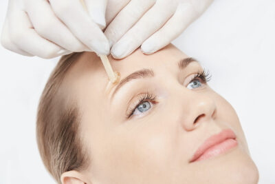 Woman having her eyebrows waxed by an aesthetician