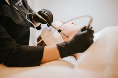 Woman receiving micro-current treatment to the side of her face.